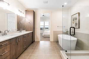 Bathroom with vanity, vaulted ceiling, tile patterned flooring, ceiling fan, and a tub