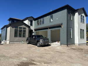 Rear view of property featuring a garage and dirt driveway