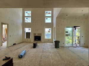 Unfurnished living room with a towering ceiling and a fireplace