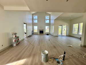 Unfurnished living room featuring light wood finished floors, a high ceiling, plenty of natural light, and a textured ceiling
