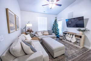 Living room with vaulted ceiling, ceiling fan, and dark hardwood / wood-style floors