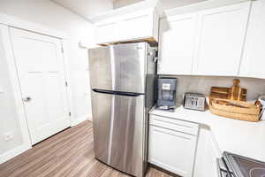 Kitchen featuring white cabinets, light hardwood / wood-style floors, and stainless steel refrigerator