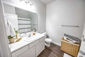 Bathroom featuring hardwood / wood-style flooring, vanity, and toilet