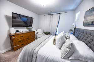 Bedroom featuring light colored carpet and a textured ceiling