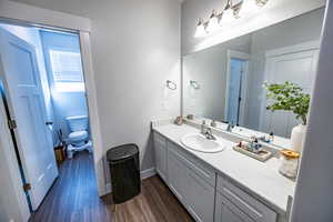 Bathroom with hardwood / wood-style floors, vanity, and toilet