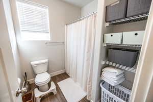 Bathroom featuring hardwood / wood-style floors, a shower with curtain, and toilet