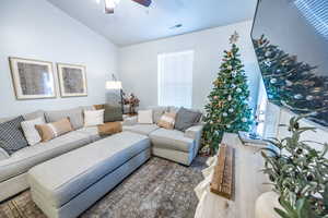 Living room featuring wood-type flooring, vaulted ceiling, and ceiling fan