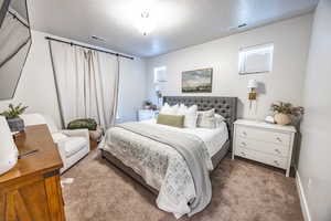 Bedroom featuring light colored carpet and a textured ceiling