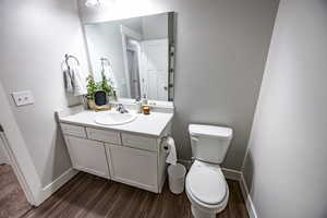 Bathroom with hardwood / wood-style flooring, vanity, and toilet