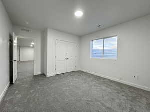 Unfurnished bedroom featuring dark colored carpet and a closet