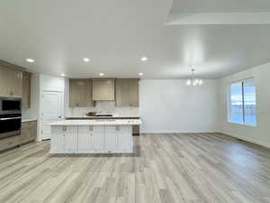 Kitchen featuring backsplash, a spacious island, a notable chandelier, custom range hood, and stainless steel appliances