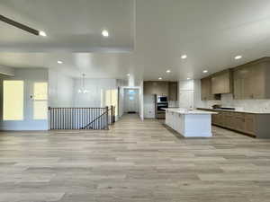 Kitchen with appliances with stainless steel finishes, a center island, decorative light fixtures, and light hardwood / wood-style floors