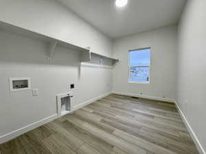 Clothes washing area with hookup for an electric dryer, hookup for a washing machine, and light hardwood / wood-style flooring