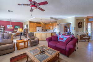 Tiled living room with crown molding, ceiling fan, and a textured ceiling