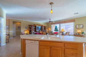 Kitchen featuring sink, white dishwasher, a textured ceiling, decorative light fixtures, and light tile patterned floors