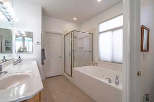 Bathroom with tile patterned floors, vanity, and shower with separate bathtub