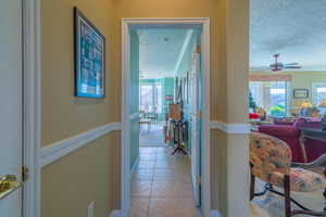 Corridor with light tile patterned floors, a textured ceiling, and crown molding