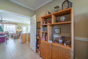 Home office featuring crown molding, ceiling fan, and light tile patterned flooring