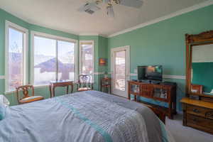 Carpeted bedroom featuring access to outside, multiple windows, ceiling fan, and ornamental molding