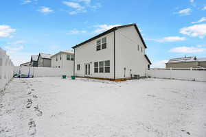 Snow covered rear of property featuring central air condition unit and a trampoline