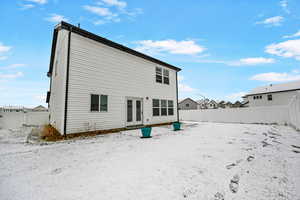 Snow covered rear of property featuring french doors