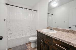 Full bathroom with hardwood / wood-style floors, vanity, toilet, and shower / bath combo with shower curtain