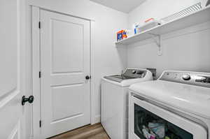 Laundry room with washing machine and dryer and light hardwood / wood-style flooring