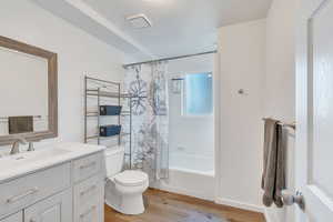 Full bathroom with shower / bath combination with curtain, vanity, hardwood / wood-style flooring, and toilet