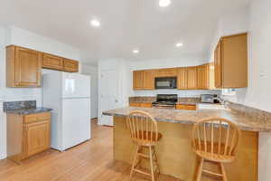 Kitchen featuring kitchen peninsula, a breakfast bar, black appliances, and sink