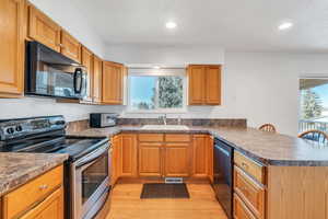 Kitchen featuring black appliances, bamboo floors, kitchen peninsula, and sink