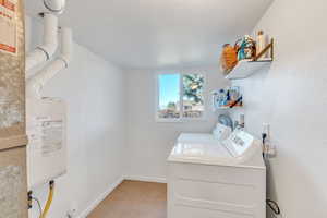 Laundry room with washing machine and dryer and light tile patterned floors