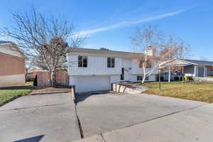 Bi-level home featuring a garage and a front lawn