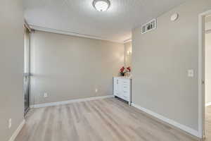 Unfurnished room with a textured ceiling and light wood-type flooring