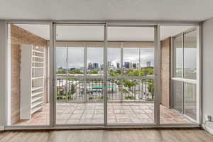 Doorway to outside with expansive windows, wood-type flooring, and a textured ceiling