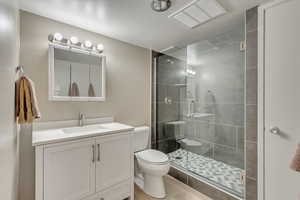 Bathroom with vanity, toilet, and a shower with shower door