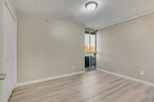 Unfurnished room featuring a textured ceiling and light hardwood / wood-style flooring