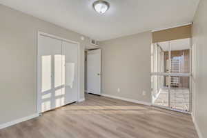 Unfurnished bedroom featuring light wood-type flooring, a textured ceiling, and a closet