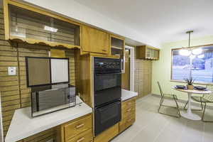 Kitchen with pendant lighting, black double oven, and light tile patterned flooring