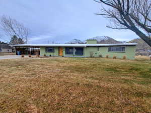 View of front of property featuring a mountain view, a front lawn, and a carport