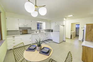 Kitchen featuring tasteful backsplash, white appliances, sink, light tile patterned floors, and white cabinets