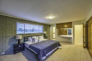 Carpeted bedroom featuring brick wall