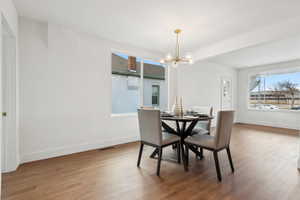 Dining space featuring hardwood / wood-style flooring, a wealth of natural light, and a notable chandelier