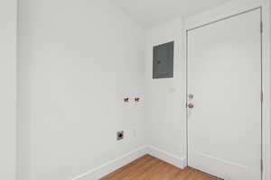 Washroom featuring electric dryer hookup, electric panel, and wood-type flooring