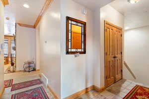 Hallway featuring light carpet and crown molding