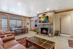 Main level Living room featuring carpet, a stone fireplace, and crown molding