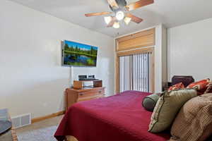 Large Basement bedroom with sliding glass doors to patio and lake. Carpeted bedroom with ceiling fan