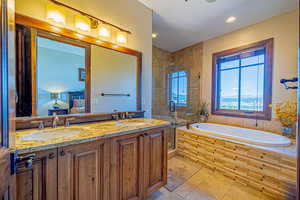 Bathroom featuring plus walk in shower, vanity, and tile patterned floors