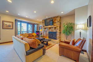 Carpeted living room with a stone fireplace