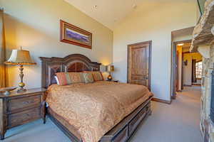 Bedroom featuring light carpet, high vaulted ceiling, and a fireplace