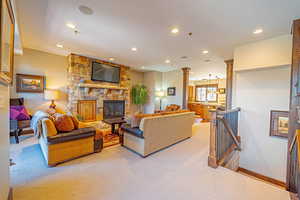 Carpeted living room with ornate columns and a stone fireplace